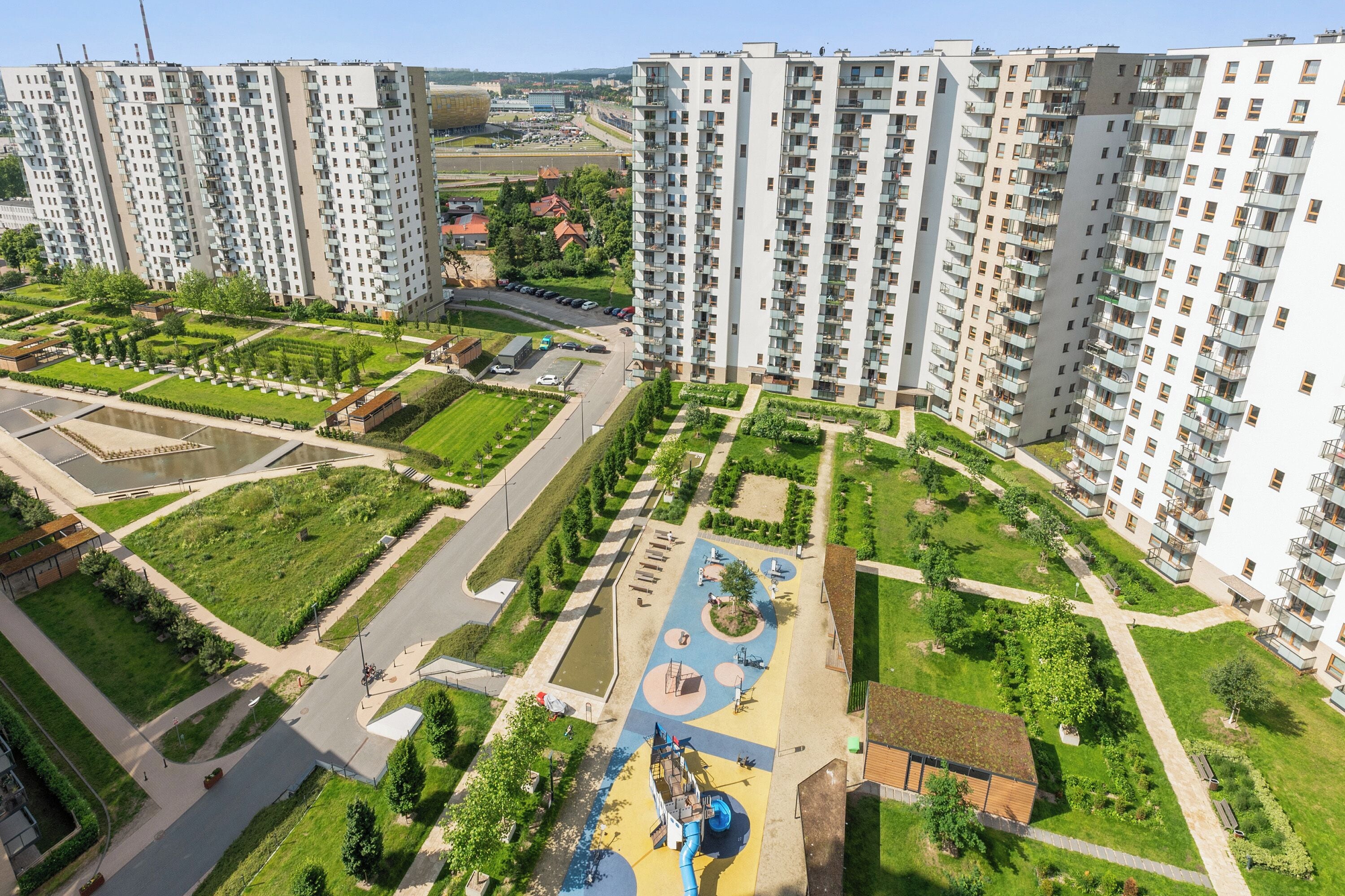 A high-rise residential building complex with multiple apartment buildings, a central courtyard with a playground, and surrounding green spaces.