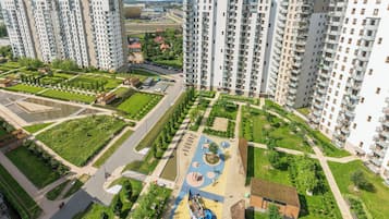 A high-rise residential building complex with multiple apartment buildings, a central courtyard with a playground, and surrounding green spaces.