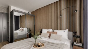A modern bedroom with a large bed, a mirror, and a wooden slat wall.