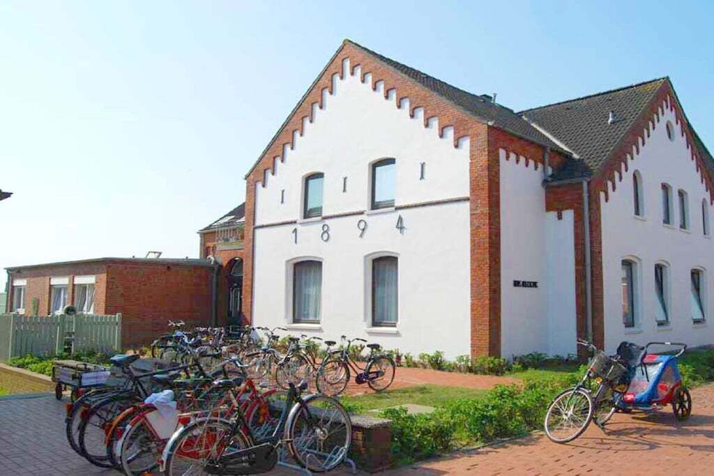 A building with a white facade and a brick section, numbered 1894, with bicycles parked in front.