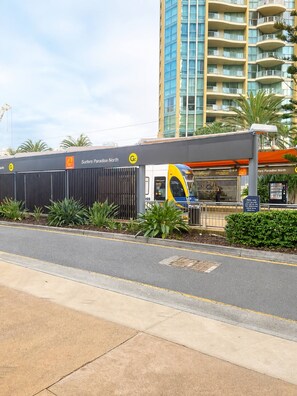 A modern building with a curved facade, a sign for 'Surfers Paradise North,' and a train station platform. - Beachfront| Ocean Views|Pool & Spa|Sleeps 5|Tennis Court| 2 Bedroom 2 Bathroom (Surfers Paradise)