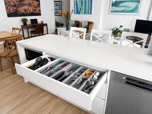 A modern kitchen with a built-in dishwasher, a white countertop, and a drawer organizer for utensils. - Beachfront| Ocean Views|Pool & Spa|Sleeps 5|Tennis Court| 2 Bedroom 2 Bathroom (Surfers Paradise)