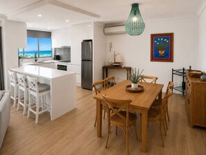 A modern kitchen with a central island, white cabinetry, and stainless steel appliances. - Beachfront| Ocean Views|Pool & Spa|Sleeps 5|Tennis Court| 2 Bedroom 2 Bathroom (Surfers Paradise)