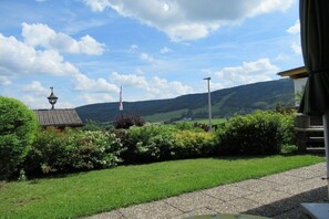 A rural landscape with a house, a flag, and a lamp post.