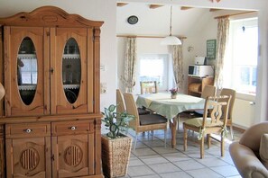 Zona pranzo con tavolo, sedie, un armadio e un lampadario.