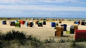 A beach with numerous colorful beach huts. - Holiday home with 3 bedrooms (Neßmersiel)