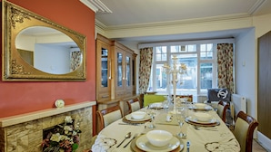 A dining room with a fireplace, a large mirror, and a table set for four. - Host and Stay - BKL Seaview House (Colwyn Bay)