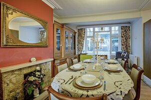 Comedor con chimenea, un espejo grande y una mesa dispuesta para cuatro.