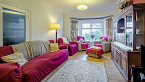 A living room with a sofa set, armchairs, a coffee table, a television, and a cabinet. - Host and Stay - BKL Seaview House (Colwyn Bay)