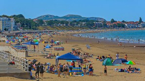 A crowded beach with people, tents, and beach umbrellas. - Host and Stay - BKL Seaview House (Colwyn Bay)