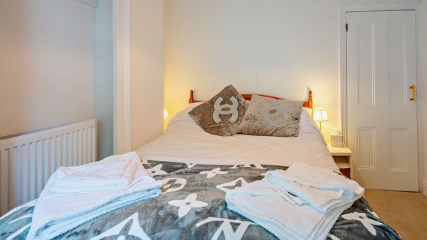 A neatly made bed with a patterned duvet, pillows, and folded towels. - Host and Stay - BKL Seaview House (Colwyn Bay)