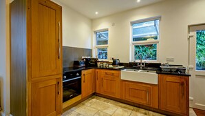 A modern kitchen with wooden cabinets, a black countertop, and a built-in oven. - Host and Stay - BKL Seaview House (Colwyn Bay)