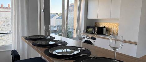 A modern kitchen with a dining area, equipped with a microwave, sink, and a view of the outside.
