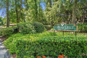 A sign for Harbour Oaks with lush greenery and trees in the background. - 3BR Harbour Oaks • Walk to Pier Village & Beach • Pool (St Simons)