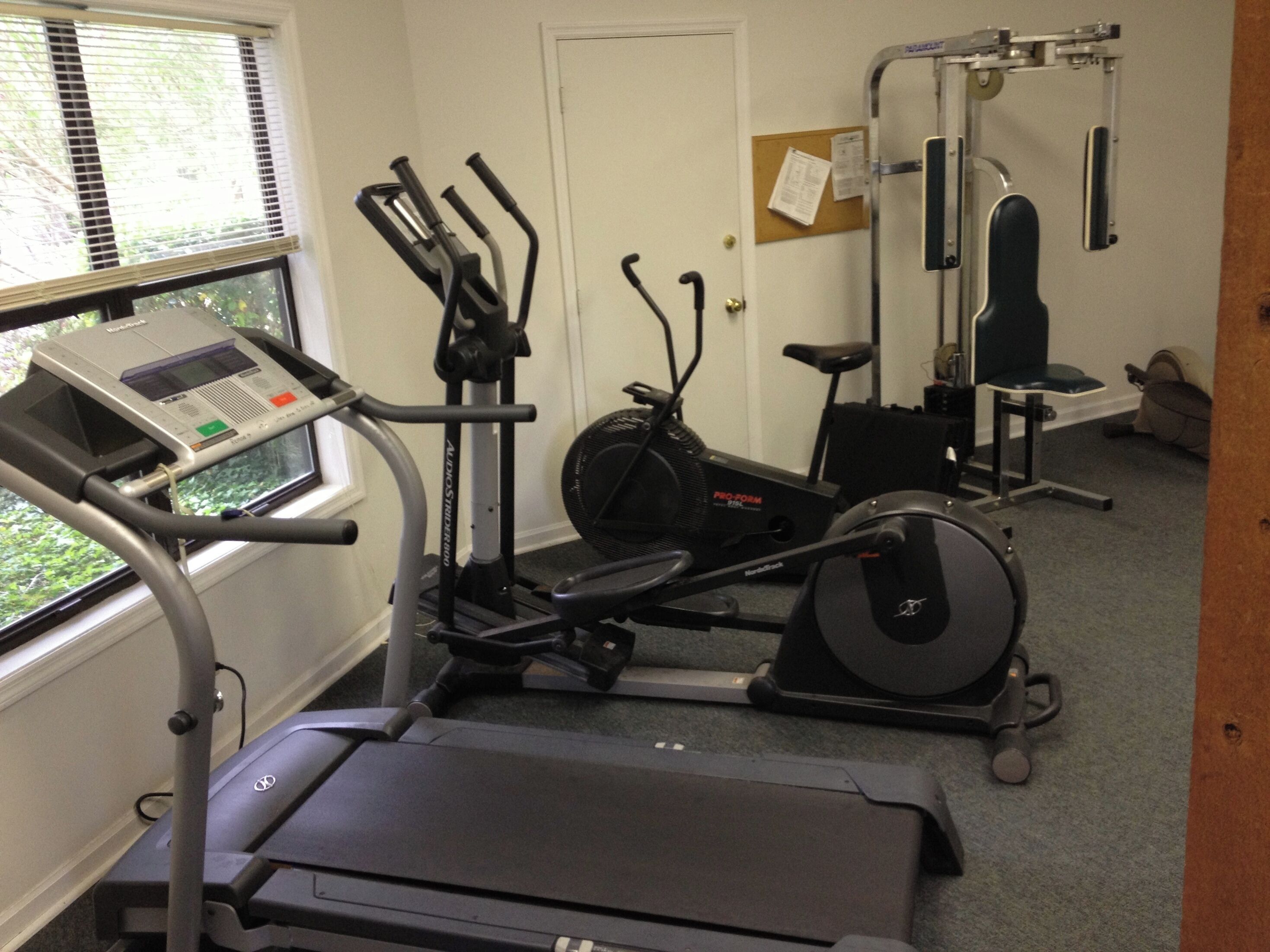A gym with cardio equipment including a treadmill, elliptical, and stationary bike.