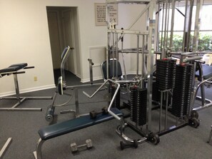 A gym with weightlifting equipment, benches, and dumbbells. - 3BR Harbour Oaks • Walk to Pier Village & Beach • Pool (St Simons)
