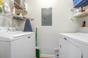 A laundry room with two washing machines, a utility wall with storage shelves, and a mop. - 3BR Harbour Oaks • Walk to Pier Village & Beach • Pool (St Simons)