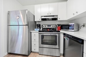 A compact kitchen with a stainless steel refrigerator, oven, microwave, and dishwasher. - 3BR Harbour Oaks • Walk to Pier Village & Beach • Pool (St Simons)