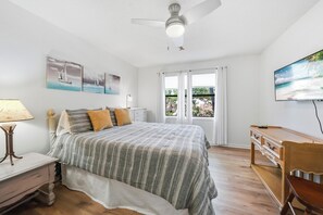 A bedroom with a bed, a nightstand, a lamp, a dresser, a ceiling fan, and a TV. - 3BR Harbour Oaks • Walk to Pier Village & Beach • Pool (St Simons)