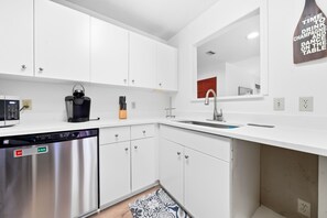 A modern kitchen with white cabinetry, a dishwasher, a coffee machine, and a sink. - 3BR Harbour Oaks • Walk to Pier Village & Beach • Pool (St Simons)