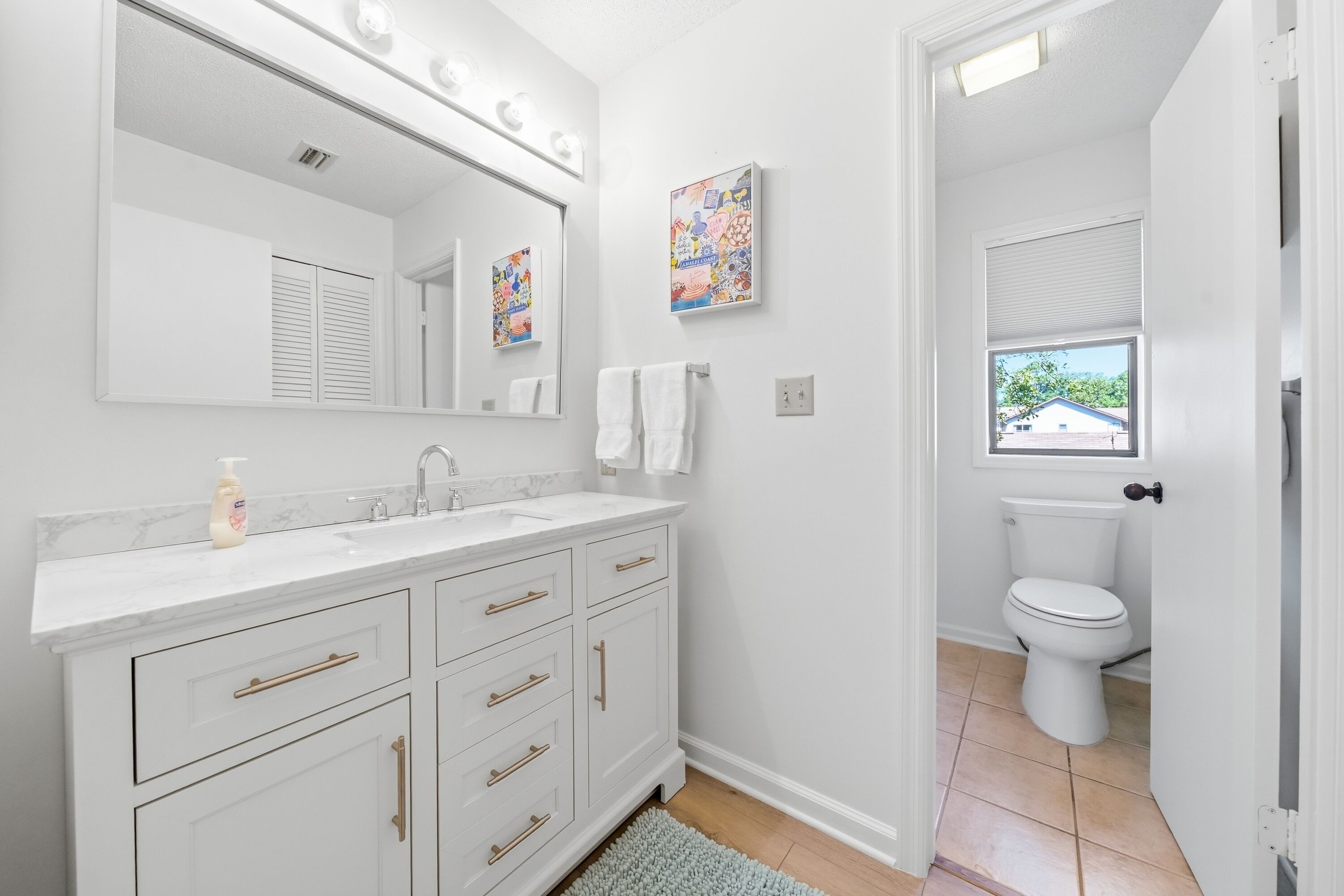 A modern bathroom with a white vanity, a large mirror, and a toilet.