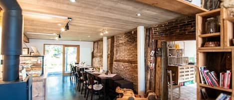 Un interior espacioso con una larga mesa de comedor, sillas mecedoras de madera y una estantería.