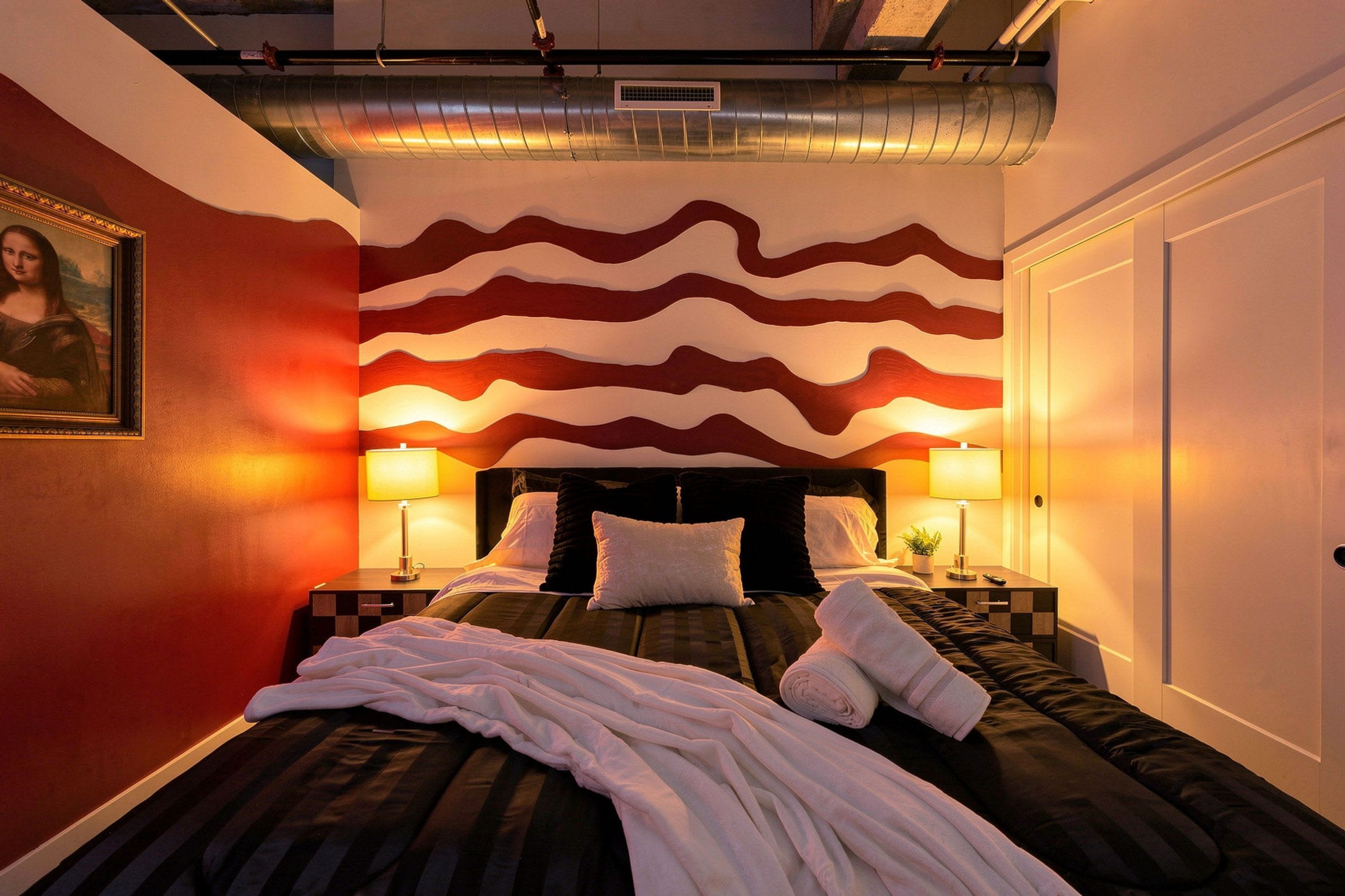 Una habitación de hotel con una cama, dos mesitas de noche, una lámpara y un cuadro en la pared.