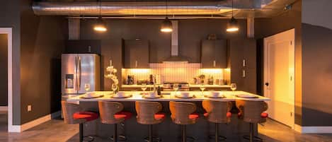 A modern kitchen with a central island, bar stools, and stainless steel appliances.