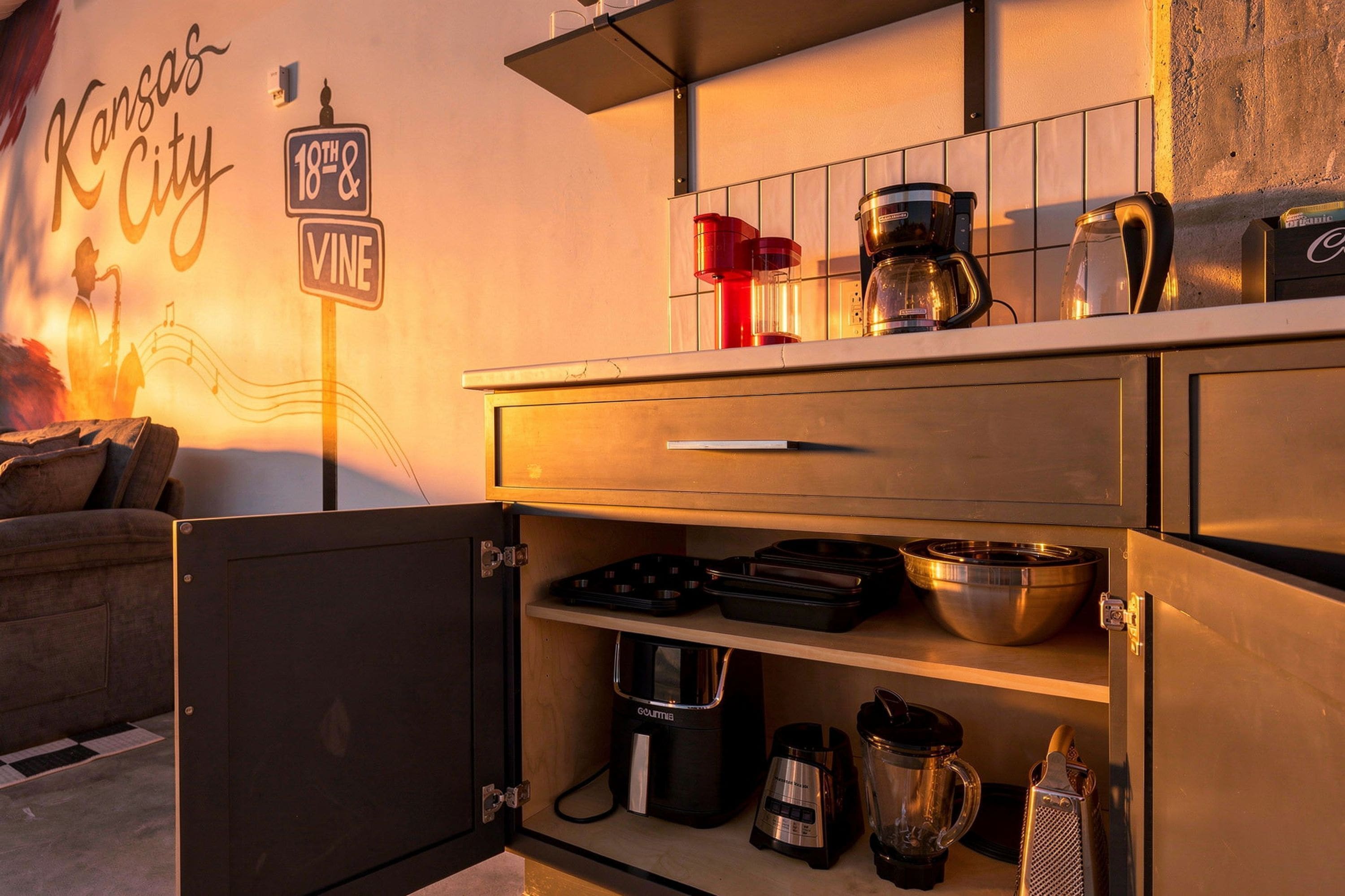 A kitchenette with a coffee maker, kettle, and various kitchen utensils.