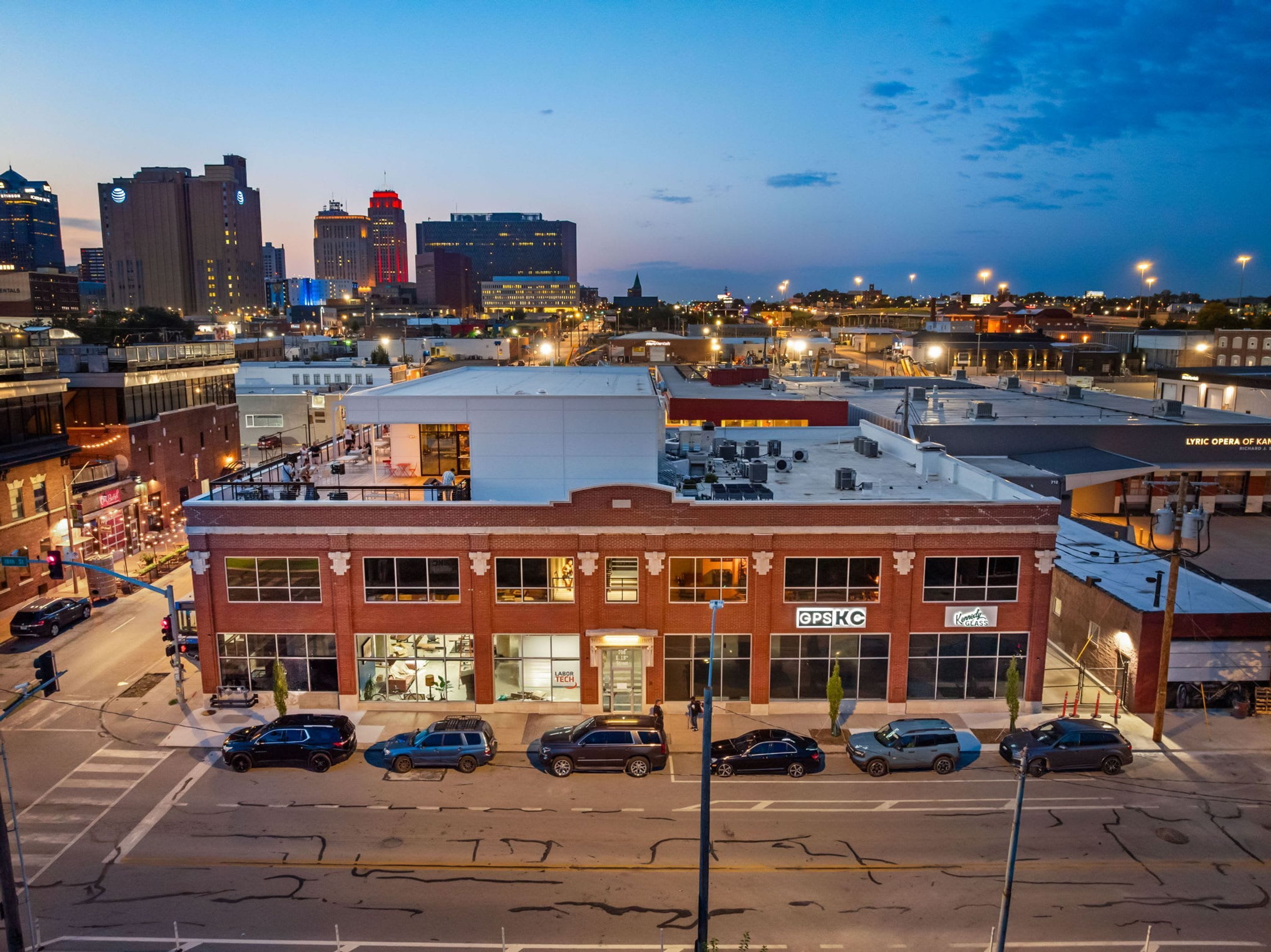 A multi-story building with a prominent 'OPS KC' sign, surrounded by parked cars and a street view.