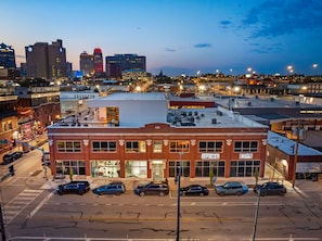 A multi-story building with a prominent 'OPS KC' sign, surrounded by parked cars and a street view. - 4BR 3BA KC Loft Collection Rooftop Bar Spa (Kansas City)