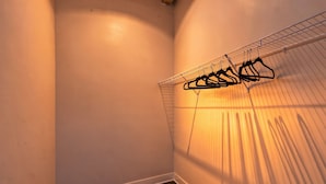 Un angolo di stanza con un'unità di scaffalature metalliche contenente diversi appendini neri.