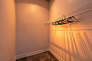 A corner of a room with a wire shelving unit holding several black hangers. - 4BR 3BA KC Loft Collection Rooftop Bar Spa (Kansas City)
