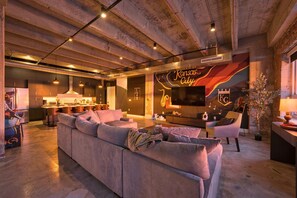 A modern living space with a large sofa, a television, and a decorative wall with 'Kansas City' text. - 4BR 3BA KC Loft Collection Rooftop Bar Spa (Kansas City)