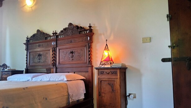 A bedroom with a wooden bed, a bedside lamp, and a nightstand.