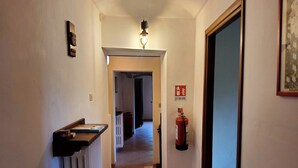 A hallway with a radiator, a fire extinguisher, and a door frame.