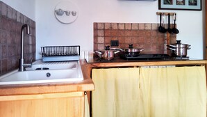 A kitchen with a sink, stove, and various pots and pans.