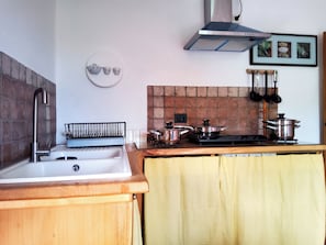 A kitchen with a sink, stove, and various pots and pans.