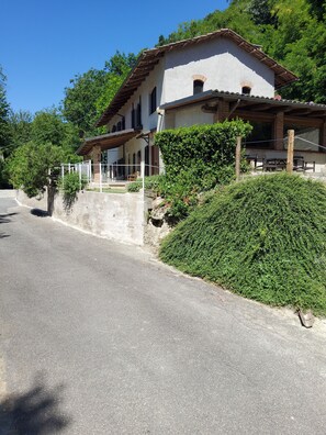 A two-story building with a balcony, a stone wall, and a large bush in front. - Privacy, tranquility, relaxation, nature, culture, and traditions. Pet-friendly (Piemonte)