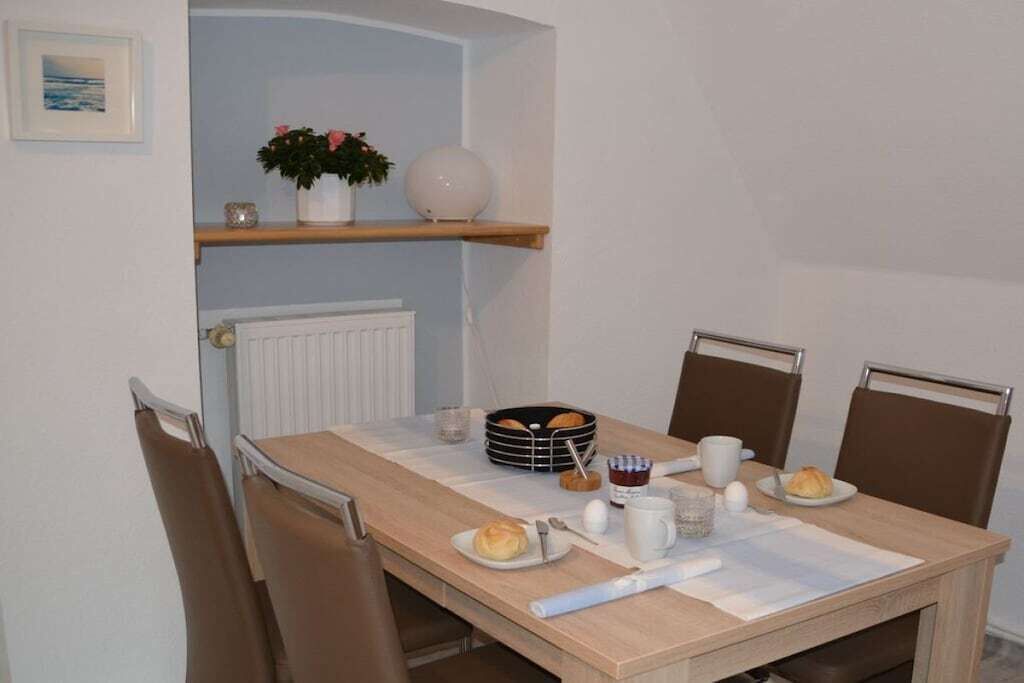 A dining area with a table set for breakfast, including bread, eggs, and a coffee cup.