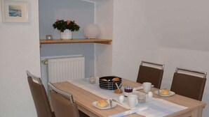 Ein Essbereich mit einem für das Frühstück gedeckten Tisch, darunter Brot, Eier und eine Kaffeetasse.