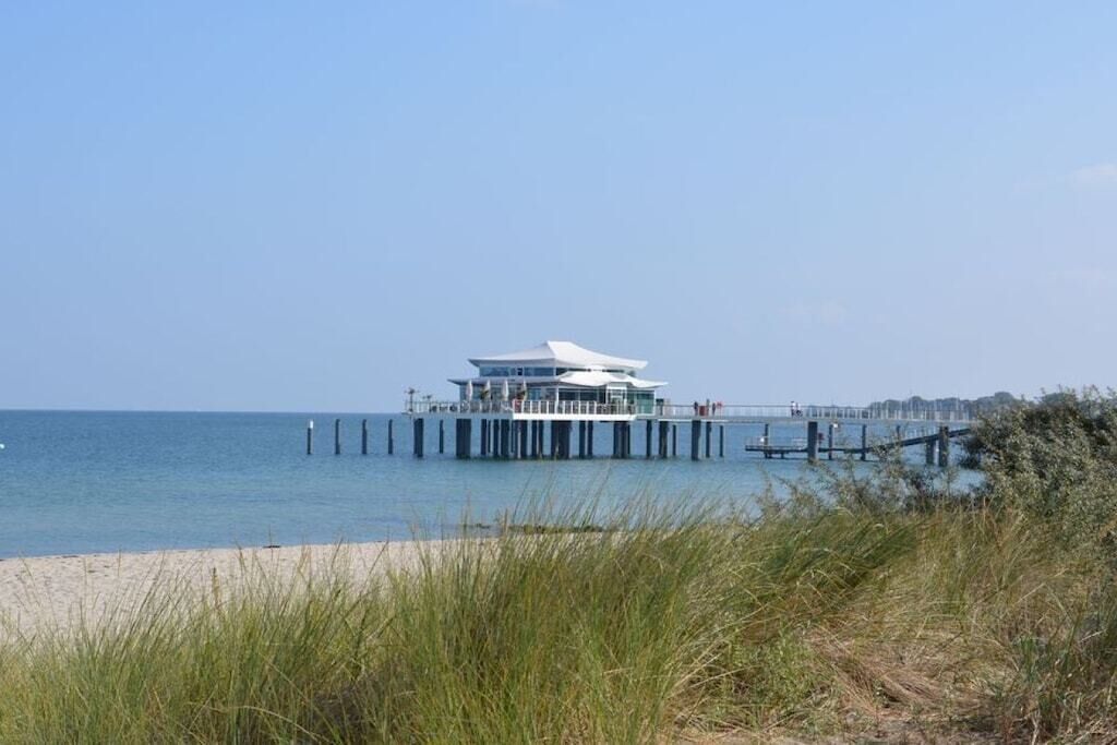 A modern building with a flat roof, situated on a pier extending into the water.