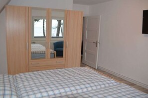 A bedroom with a bed, a wardrobe with a mirror, and a door. - Holiday apartment with 2 bedrooms (Timmendorfer Strand)