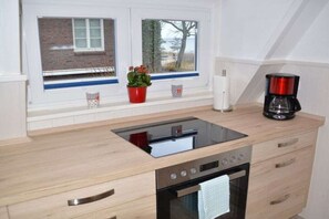 A modern kitchen with a built-in stove, oven, and a coffee maker on the countertop. - Holiday apartment with 2 bedrooms (Timmendorfer Strand)
