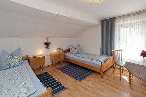 Une chambre avec deux lits, un plancher en bois, une petite table et une chaise.