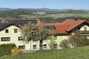 Un edificio con pannelli solari sul tetto, immerso nel verde e con vista su dolci colline.