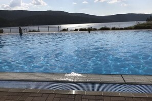 En swimmingpool med utsikt över en sjö och kullar.