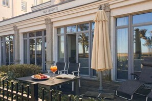 An outdoor seating area with a table, chairs, and an umbrella. - Holiday apartment in Binz with swimming pool (Binz)