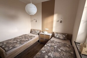 Ett sovrum med två enkelsängar, ett litet bord med en skål och en hängande lampa.