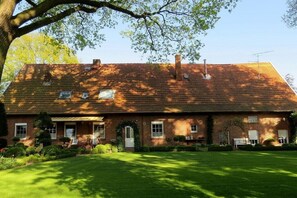 Ein Backsteinhaus mit geneigtem Dach, einer Haustür und einem kleinen Garten.